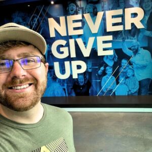 Alan Bonde in front of never give up banner