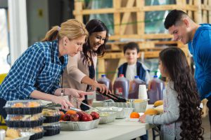 Two women serve family at soup kitchen