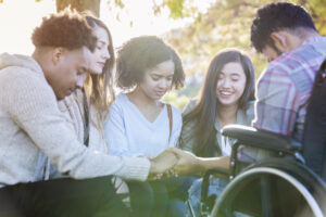 Diverse group of college friends hold hands and pray together on campus.