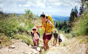 Happy family with small children hiking outdoors in summer nature.
