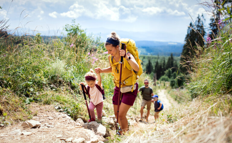Happy family with small children hiking outdoors in summer nature.